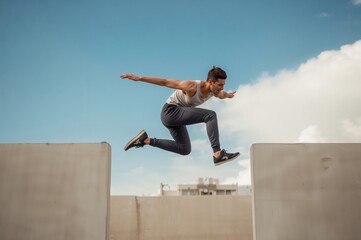 Parkour athlete suspended mid-air leaps across pale concrete urban landscape