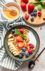 Delicious granola with yogurt, fresh berries and banana slices enjoying healthy breakfast