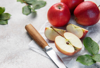 Freshly cut red apples on baking paper with knife and leaves