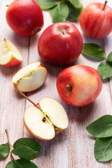 Red apples and slices on light wood background