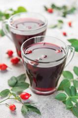 Drinking hot rosehip tea with berries and leaves