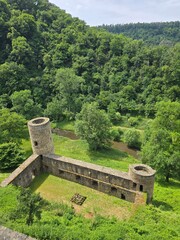 Stone castle ruin with round towers in green forest valley