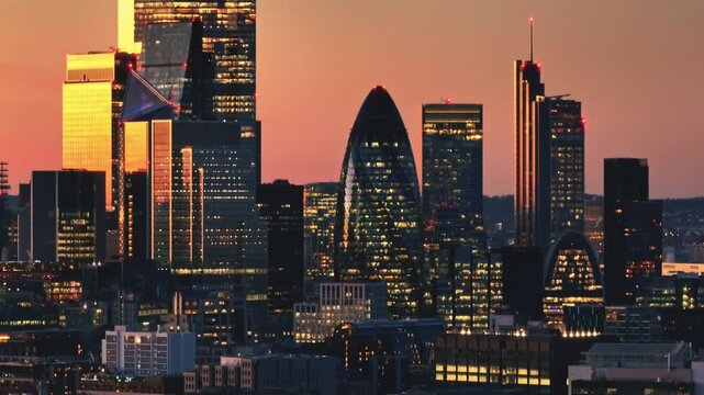 England, London: Aerial view of the illuminated London skyline during a vibrant sunset, showcasing famous landmarks and modern buildings, capturing the dynamic energy of the city's financial district