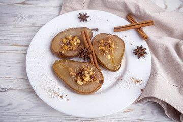 baked pear with honey, cheese, and nuts on a white plate.Baked pear with honey, cheese, and nuts on a white plate. The dish is presented for serving in a restaurant.