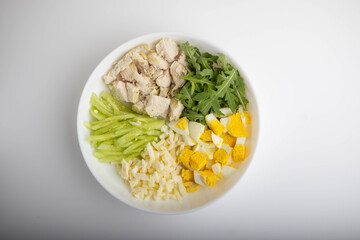 separate ingredients for a salad with egg, cheese, chicken fillet, and arugula on a plate