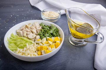 separate ingredients for a salad with egg, cheese, chicken fillet, and arugula on a plate