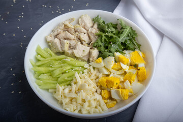 separate ingredients for a salad with egg, cheese, chicken fillet, and arugula on a plate