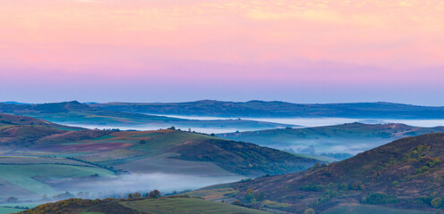 Landscape with fog in the valleys between the hills in the morning