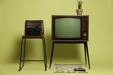 Retro TV set and other used stuff on olive background