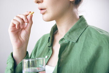 Sick young woman holding medicine and glass of water.