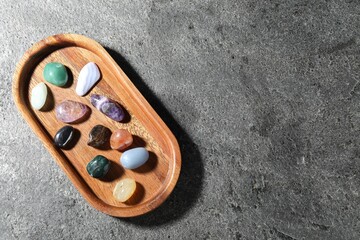 Different beautiful gemstones on grey table, top view. Space for text