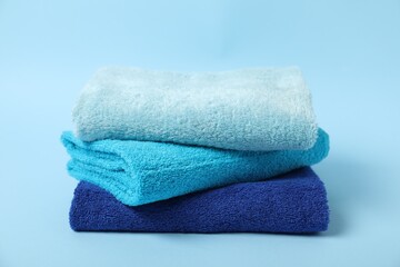 Stack of fresh terry towels on light blue background