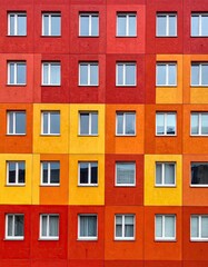 Fototapeta premium Colorful geometric building facade with repeating windows in red and yellow.