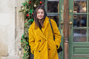 Woman in yellow winter coat smiling outdoors. Holiday season.