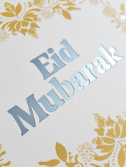 Obraz premium Eid Mubarak greeting card with silver lettering and gold floral decorations creating festive holiday scene