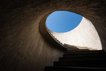 Abstract concrete spiral staircase leading to a skylight