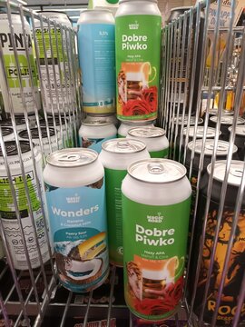 Cans of craft beer branded as Dobre Piwko and Wonders on a metal shelf in a liquor store or supermarket aisle