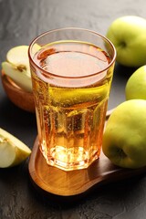 Delicious cider in glass and apples on black table, closeup