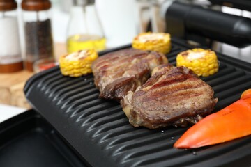 Electric grill with tasty meat and vegetables, closeup