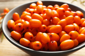 Fresh sea buckthorn berries in bowl on table, closeup