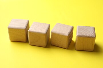 Blank wooden cubes on yellow background, closeup