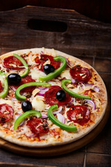 Pizza with salami, mozzarella cheese and jalapeno pepper. Wooden background. Soft focus.	