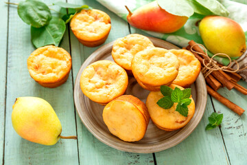 Freshly baked pear muffins with cinnamon and mint on rustic wooden table