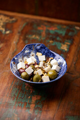 Green and kalamata olives and feta cheese on rustic wooden background. Soft focus.	
