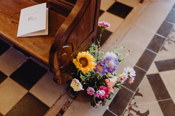 Livret de messe de mariage sur le banc de l'&eacute;glise d&eacute;cor&eacute;e de fleurs color&eacute;es