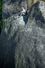 Hiker resting on giant rock during mountain trek, enjoying nature and outdoor adventure