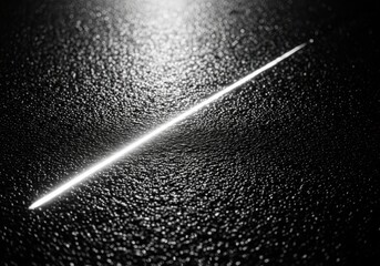 A single bright white line diagonally across a dark textured surface