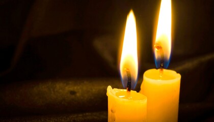 Two candles ablaze in the dark, offering warmth and gentle light in the shadows