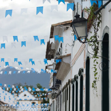 Rua com fachadas coloniais decoradas com bandeirinhas coloridas em cidade hist&oacute;rica brasileira.