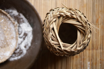 Processo tradicional da farinha de mandioca: tacho de torrar farinha, farinha branca e tipiti de palha usado para prensar a mandioca ralada.