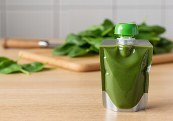Baby spinach puree pouch on wooden table