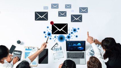 Team of office workers engaged in a discussion about email communication strategy, supported by data analytics visualized on a modern workspace table. Trope
