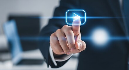 A hand pressing a glowing blue play button in a digital interface with a suit and laptop behind it