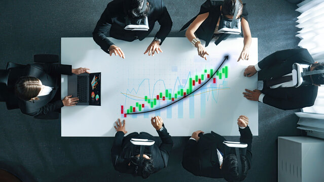 A diverse group of business professionals uses virtual reality headsets to analyze data on a digital screen in a modern office setting. Axiom