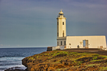 Landscape with white lighthouse under the sunlight on the African coast of the ocean.