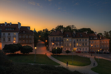 Pomarańczowy zachód słońca nad zabytkowymi kamienicami starego miasta w Warszawie przy ulicy Mostowej