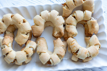 Close-Up of U-Shaped Apple Cookies on a Rectangular Plate on a White Wooden Surface