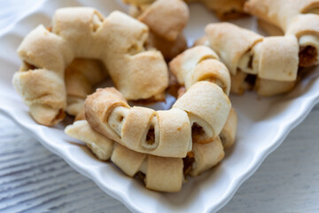 Close-Up of U-Shaped Apple Cookies on a Rectangular Plate on a White Wooden Surface