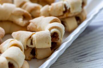 Close-Up of U-Shaped Apple Cookies on a Rectangular Plate on a White Wooden Surface