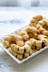 Close-Up of U-Shaped Apple Cookies on a Rectangular Plate on a White Wooden Surface