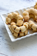 Close-Up of U-Shaped Apple Cookies on a Rectangular Plate on a White Wooden Surface