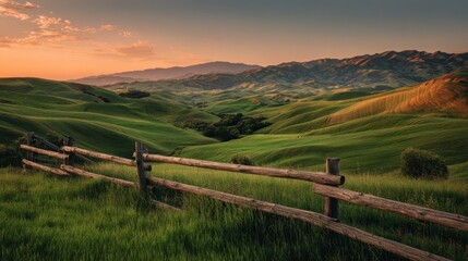 Rolling green hills in a vast countryside landscape, a rustic wooden fence marking the foreground as the warm sunset light casts golden hues across the serene tuscan valleys