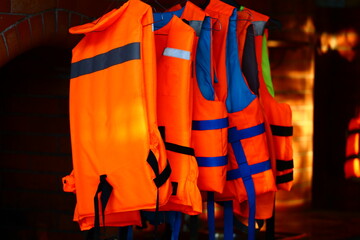A collection of life jackets hung on a metal rack, ready for use