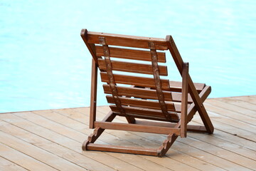 A wooden chair placed beside a pool, perfect for relaxation or outdoor living