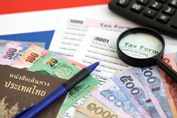 Thai baht money bills and calculator with tax form on flag. Taxation and accounting concept