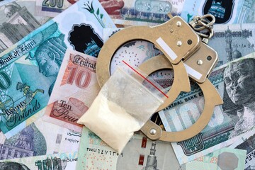 Egyptian pound currency money bills and cocaine pack with handcuffs. The concept of drug crimes